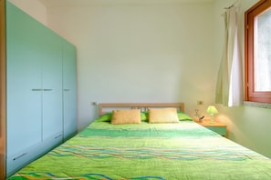 A bedroom with a bed, a nightstand, a lamp, and a wardrobe.