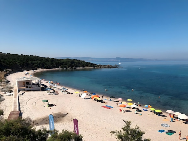 A beach with a lifeguard tower, umbrellas, and a clear view of the sea.