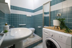 Une salle de bain équipée d’un lavabo, de toilettes et d’un lave-linge.
