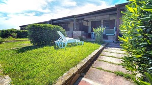 Una casa con veranda, prato e muro in pietra.