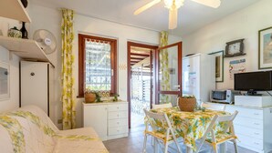 Una cucina compatta con zona pranzo, ventilatore a soffitto e televisore.