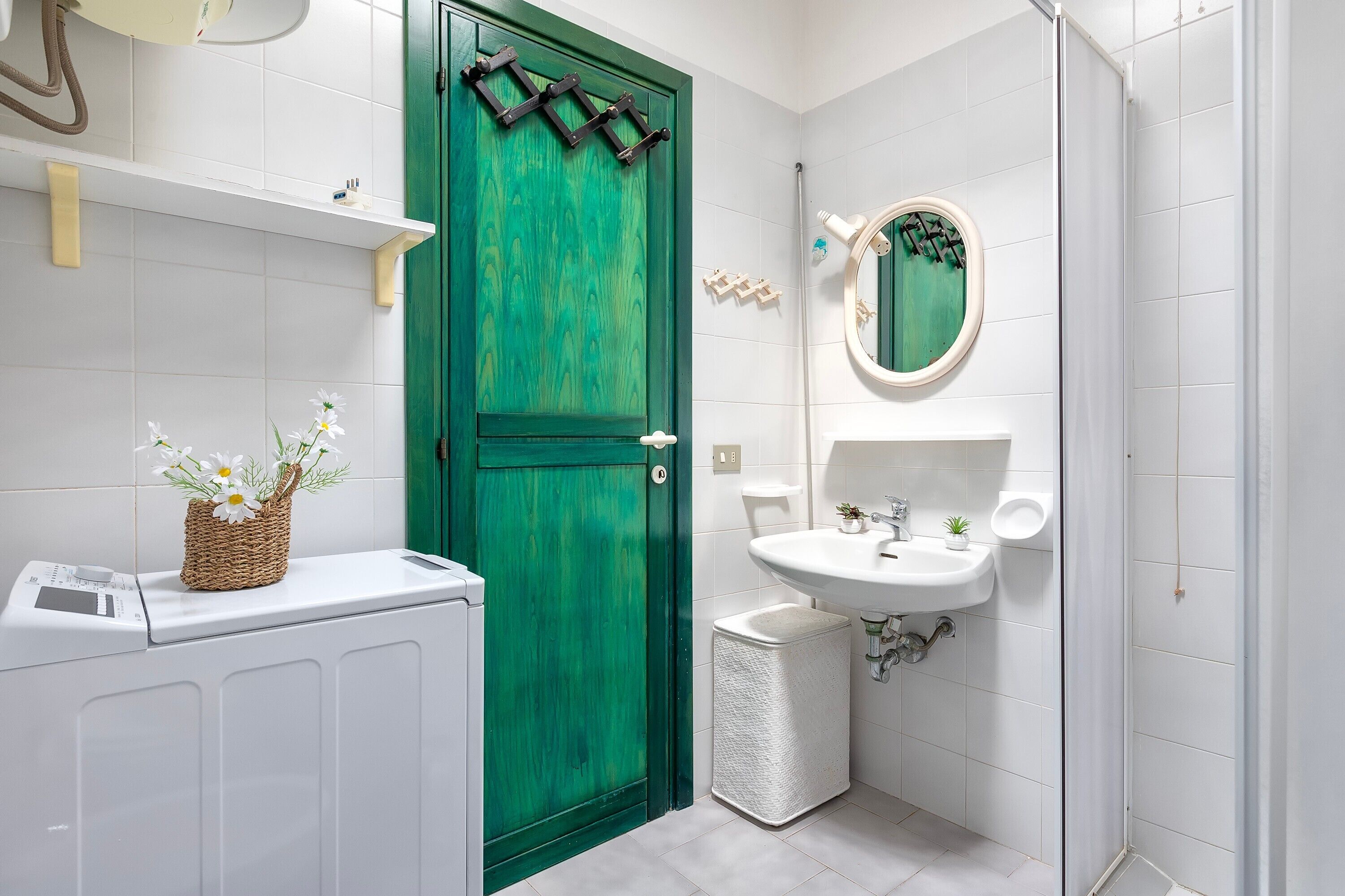 A bathroom with a green door, a white sink, and a mirror.