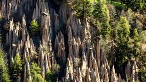 Un paysage accidenté, parsemé d’arbres, avec de hautes formations rocheuses aux contours pointus.