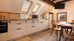 A modern kitchen with skylights, wooden beams, and a dining area with a table and chairs. - Apartment 'Hofer Hitt 2' with Mountain View, Shared Garden and Wi-Fi (Klobenstein)