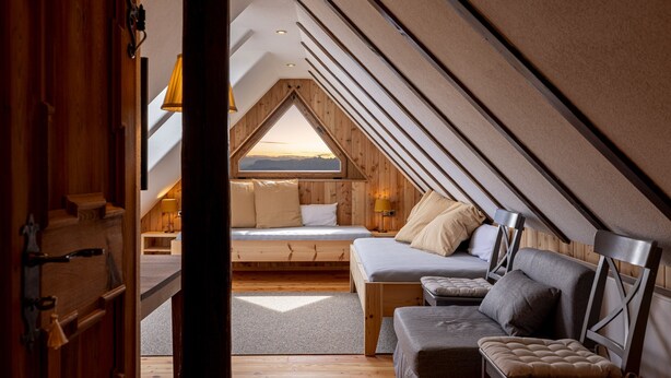 A cozy attic bedroom with a sloped ceiling, a bed, a sofa, and a view of the sky. - Apartment 'Hofer Hitt 2' with Mountain View, Shared Garden and Wi-Fi (Klobenstein)