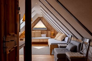 A cozy attic bedroom with a sloped ceiling, a bed, a sofa, and a view of the sky. - Apartment 'Hofer Hitt 2' with Mountain View, Shared Garden and Wi-Fi (Klobenstein)