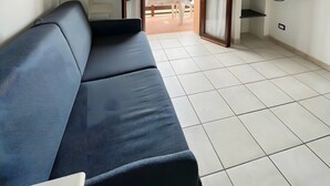 Una sala de estar moderna con un sofá, un televisor y vistas al exterior.