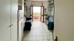 Un pasillo con suelo de baldosas, un sofá, una cama y un espejo grande en la pared.