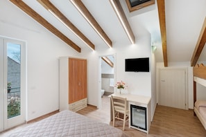 A bedroom with a bed, a desk, a chair, a TV, and a wardrobe.