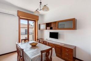A dining area with a table, chairs, a chandelier, a TV, and wooden cabinets. - Apartment 'Il Sentiero Degli Dei' with Balcony, Wi-Fi and Air Conditioning (Agerola)