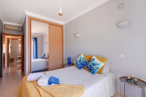 A hotel room with a bed, a bedside table, a mirror, and a door leading to a bathroom.