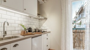 A modern kitchen with white cabinets, a stainless steel sink, and a view of a residential building through a window. - Apartment 'Meliti Kalamata' with Mountain View, Wi-Fi and Air Conditioning (Unknown)