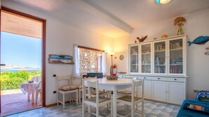 Una stanza con un tavolo da pranzo, sedie, un mobile con ante in vetro, un letto e vista sul verde.
