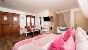 Une chambre à coucher comprenant un lit, une coiffeuse, une douche, une télévision et une armoire.