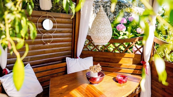 A wooden bench with cushions, a table with a bowl and candle, and a hanging lantern.