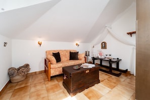 A cozy loft bedroom with a sloped ceiling, a wooden sofa, a coffee table, and a dining table with candles. - Room 'Doble Confort Dalia' with Mountain View, Shared Terrace and Wi-Fi (Rubayo)