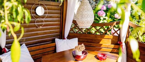 A wooden bench with cushions, a table with a bowl and candle, and a hanging lantern.