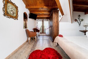 A bedroom with a bed, a red furry rug, a wooden chair, a TV, and a wooden wardrobe.
