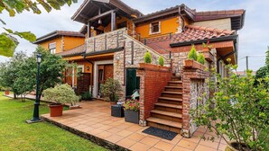 Ein zweistöckiges Haus mit einer Steinstufe, einer Veranda und einem gepflegten Garten.