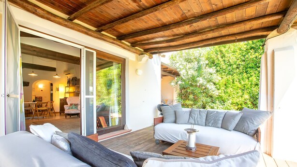 An outdoor seating area with a wooden ceiling, a sofa, and a table with a candle. - Holiday Home 'Medit' with Private Terrace, Wi-Fi and Air Conditioning (Stintino)
