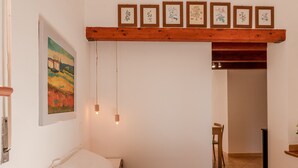 Ein Schlafzimmer mit Bett, einem Gemälde, einer Holzbalkendecke und einer Tür zu einem anderen Raum.