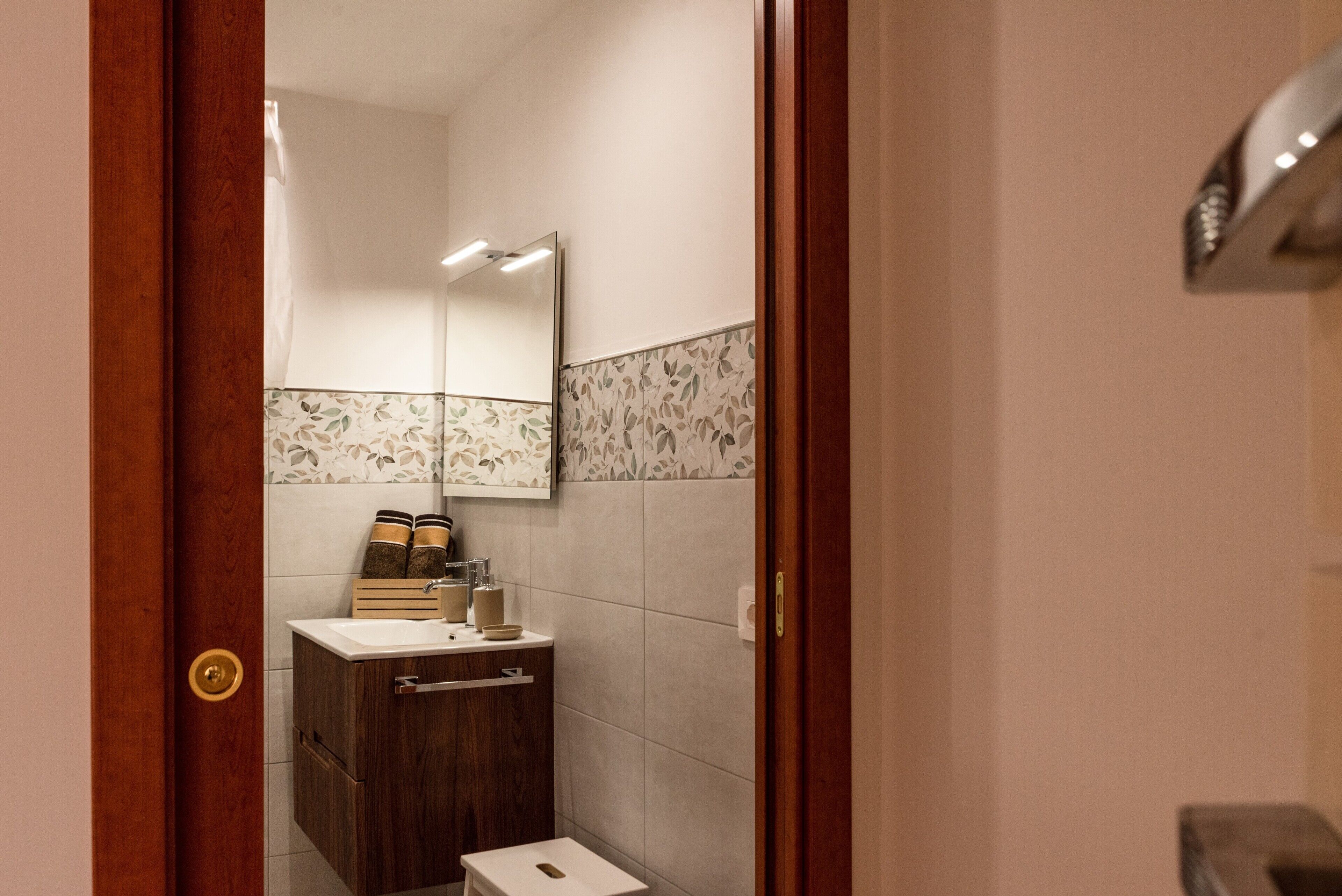 Une salle de bain avec une porte en bois, un miroir, un lavabo et des toilettes.