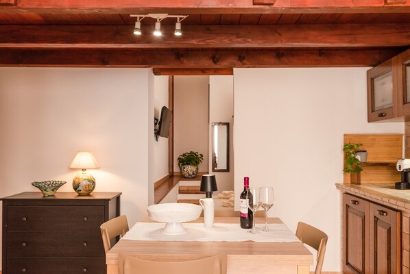 A dining area with a wooden table, chairs, a lamp, a wine bottle, and glasses.