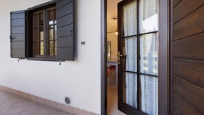 A building with a white exterior, a window with dark shutters, and a door with patterned glass. - Apartment 'Berthold' with Mountain View, Shared Terrace and Wi-Fi (Ledro)