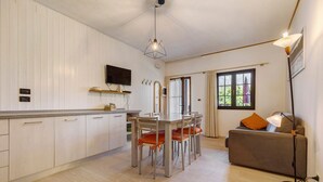 A modern kitchen with a dining table and chairs, a sofa, and a floor lamp. - Apartment 'Berthold' with Mountain View, Shared Terrace and Wi-Fi (Ledro)