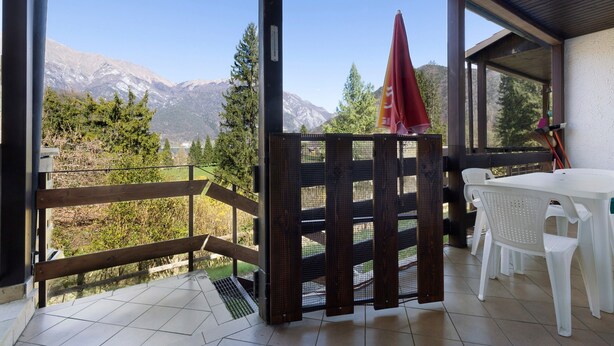 A covered outdoor area with a view of mountains, a wooden fence, and a table with chairs. - Apartment 'Berthold' with Mountain View, Shared Terrace and Wi-Fi (Ledro)
