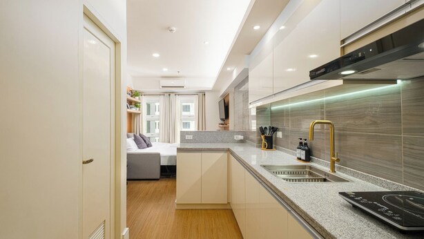 A modern kitchen with a granite countertop, stainless steel sink, and a black induction cooktop. - Great Holiday Vacation: 1BR Condo w/ 2 Queen Beds (Quezon City)