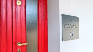 Eine rote Tür mit Messinggriffen und Schlüsselloch, und ein Schild an der Wand mit der Aufschrift 'CAMA HOLIDAY HOUSE LECCO'.