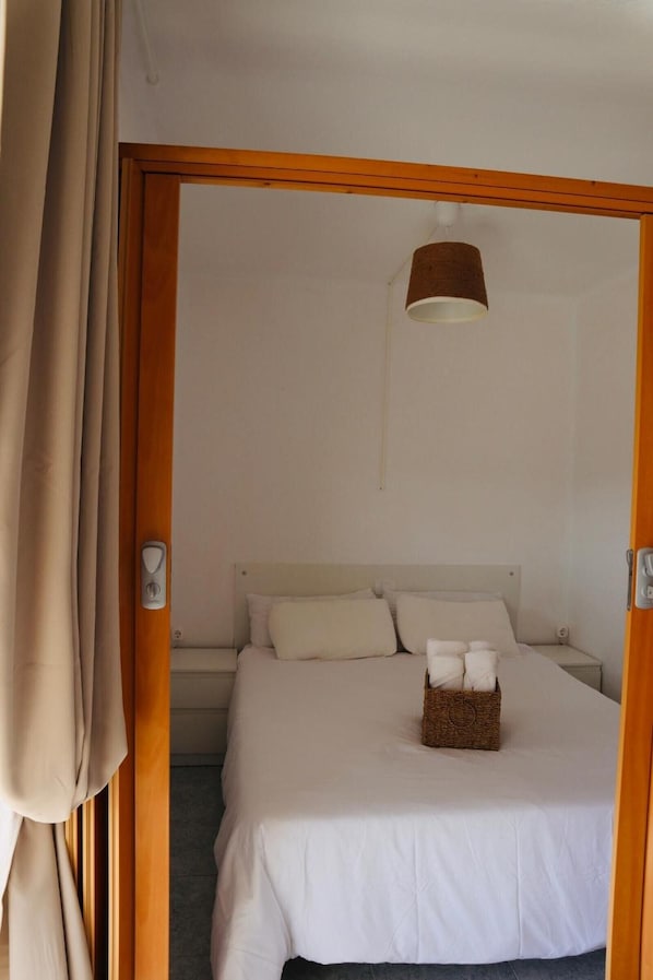 A room with a bed, a hanging light fixture, and a wooden door frame.