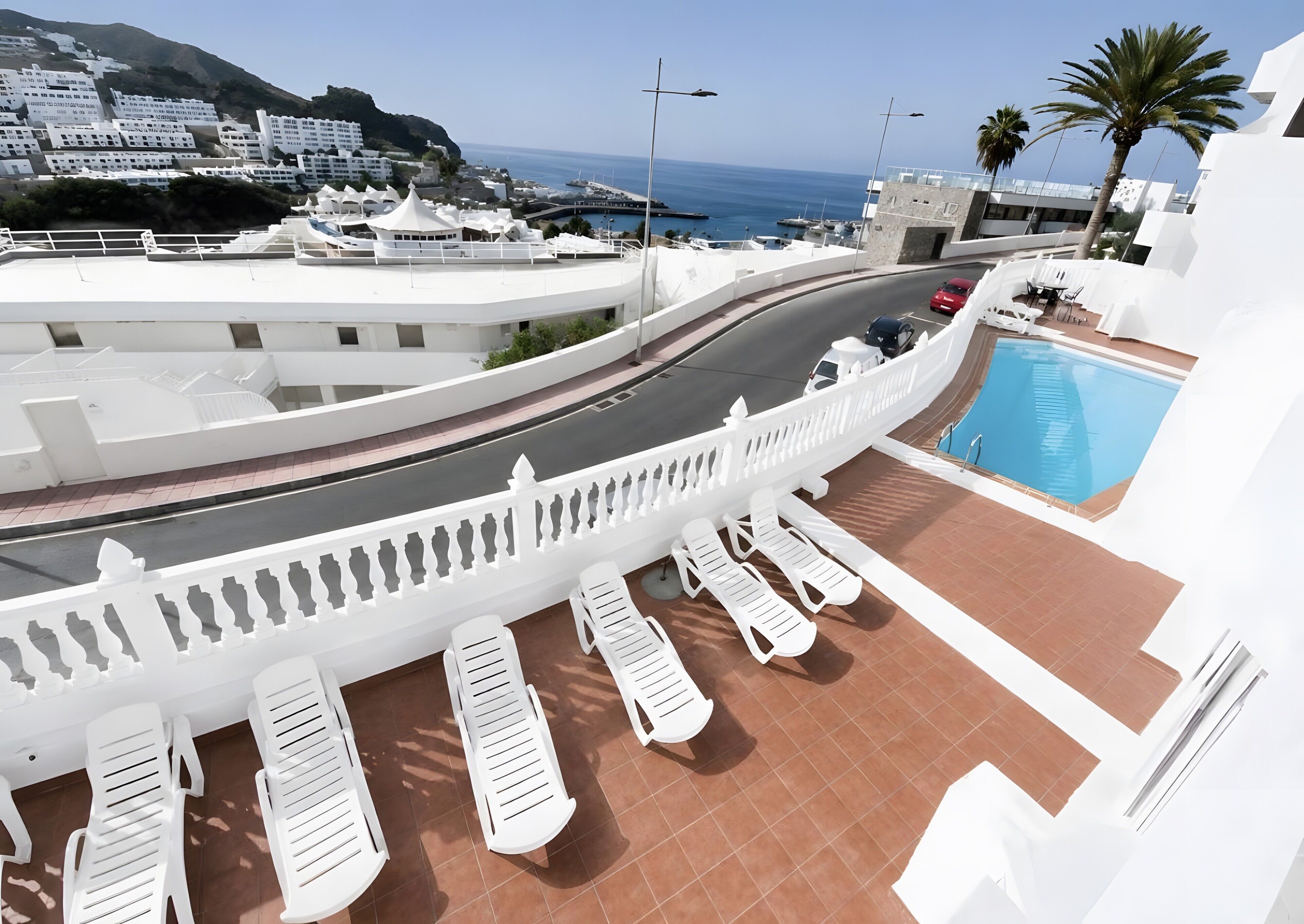 A poolside area with lounge chairs and a view of the sea.