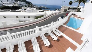 A poolside area with lounge chairs and a view of the sea.