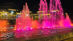 A nighttime fountain with multiple water jets illuminated in pink and orange. - Vacation 'Pura Vida' with Sea View, Shared Pool and Wi-Fi (Puerto Rico de Gran Canaria)