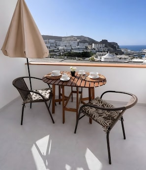 A terrace with a table set for two, chairs, and a table umbrella. - Vacation 'Pura Vida' with Sea View, Shared Pool and Wi-Fi (Puerto Rico de Gran Canaria)