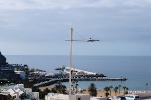 A coastal cityscape with a prominent street lamp, a pier, and a beach area.