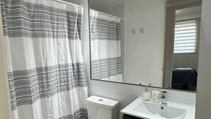 A bathroom with a striped shower curtain, a toilet, a sink, and a mirror.