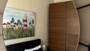 Une chambre à coucher avec un lit, un tableau représentant un phare et une armoire en bois.