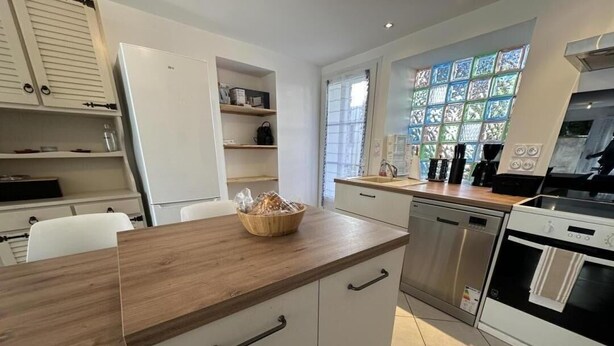 A modern kitchen with white cabinetry, a wooden countertop, and a built-in oven.