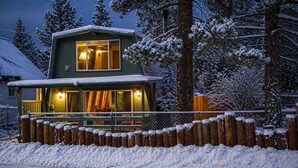 A two-story wooden cabin with a porch, surrounded by snow-covered trees. - Big Bear Getaway w/ Hot Tub, King Bed & Private Yard (Big Bear)