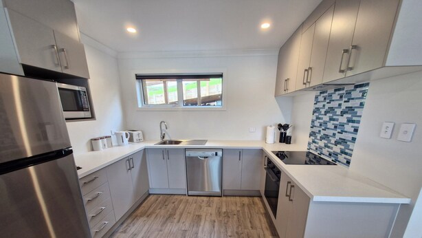 A modern kitchen with stainless steel appliances, a dishwasher, and a window above the sink.
