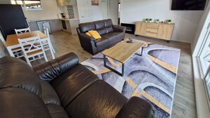 A modern living room with a brown leather sofa, a wooden coffee table, and a patterned rug.