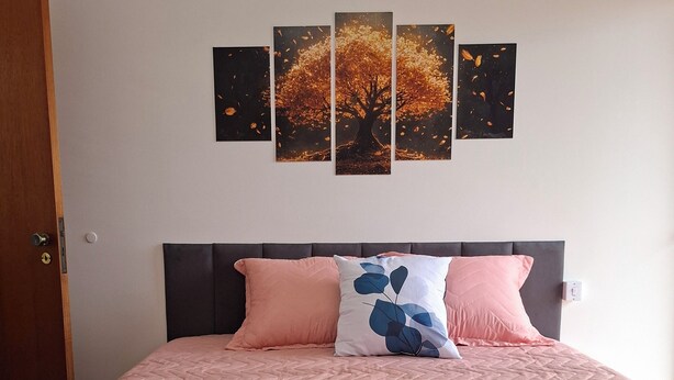 Een net opgemaakt bed met roze en blauw beddengoed, twee kussens en opgerolde handdoeken op een blauwe, gestructureerde deken.