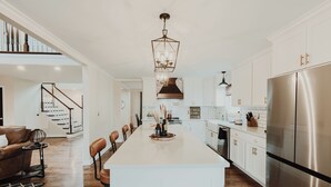 A spacious kitchen with a central island, white cabinetry, and a stainless steel refrigerator. - Heated Pool, Hot Tub, Game Room, EV charger, Sleeps 20 (Lawrenceburg)