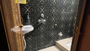 Un baño con pared de diseño blanco y negro, un lavamanos blanco y un armario de medicinas amarillo.
