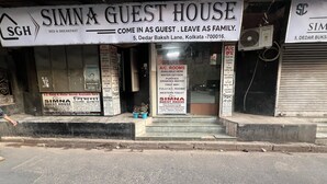 Una casa de huéspedes llamada "Simna Guest House" con un letrero que anuncia habitaciones con aire acondicionado, calentador de agua, agua potable purificada, WiFi gratuito y un baño totalmente con aire acondicionado.