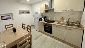 Una cocina moderna con comedor, que incluye un horno empotrado, pileta y un refrigerador compacto.