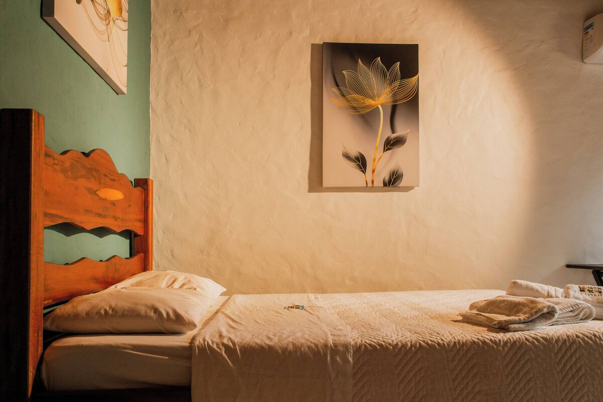 Une chambre à coucher comprenant un lit, une tête de lit, un tableau accroché au mur et une table de chevet avec une lampe.
